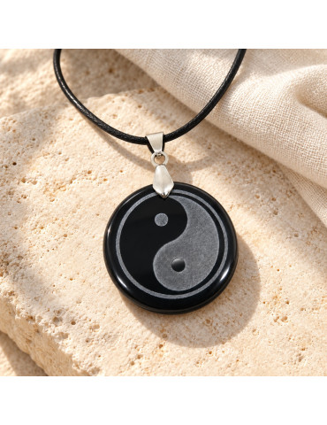 Pendentif Yin Yang en obsidienne dans une mise en scène naturelle, pierre sombre polie