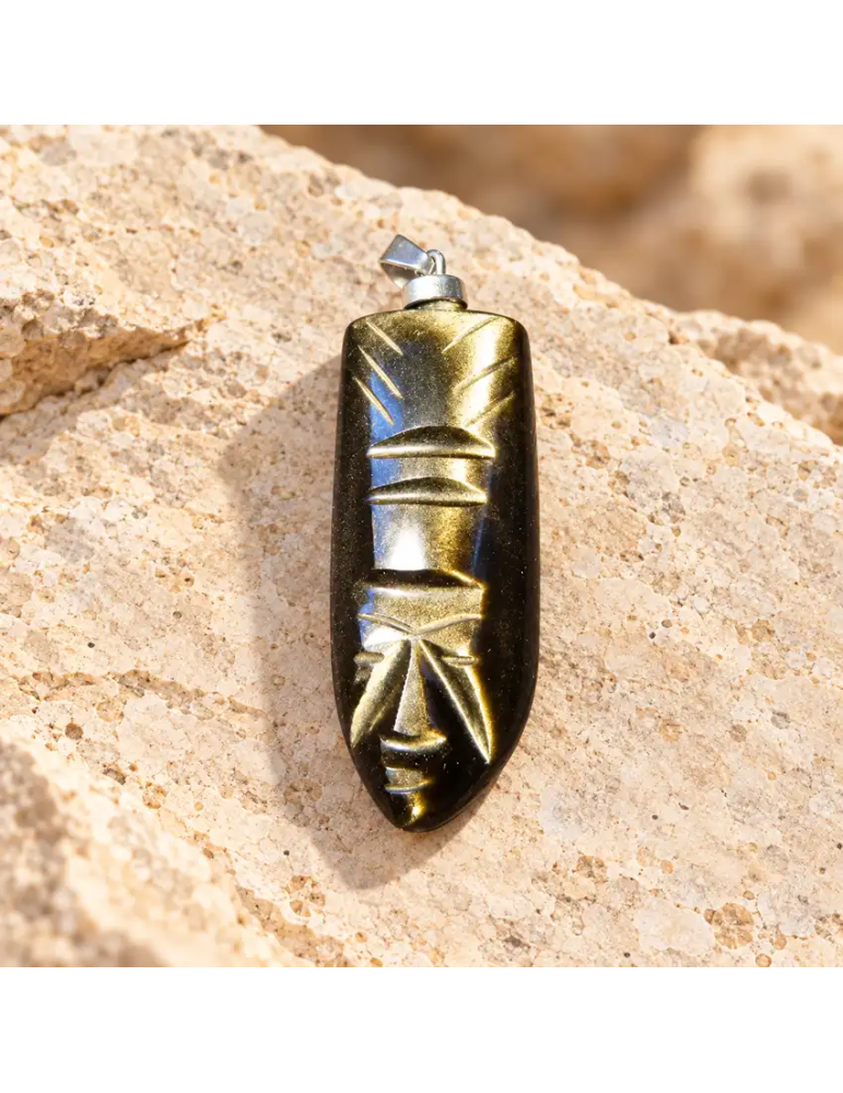 Pendentif visage aztèque sculpté en obsidienne dorée du Mexique, présenté sur pierre claire