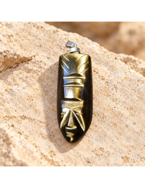 Pendentif visage aztèque sculpté en obsidienne dorée du Mexique, présenté sur pierre claire